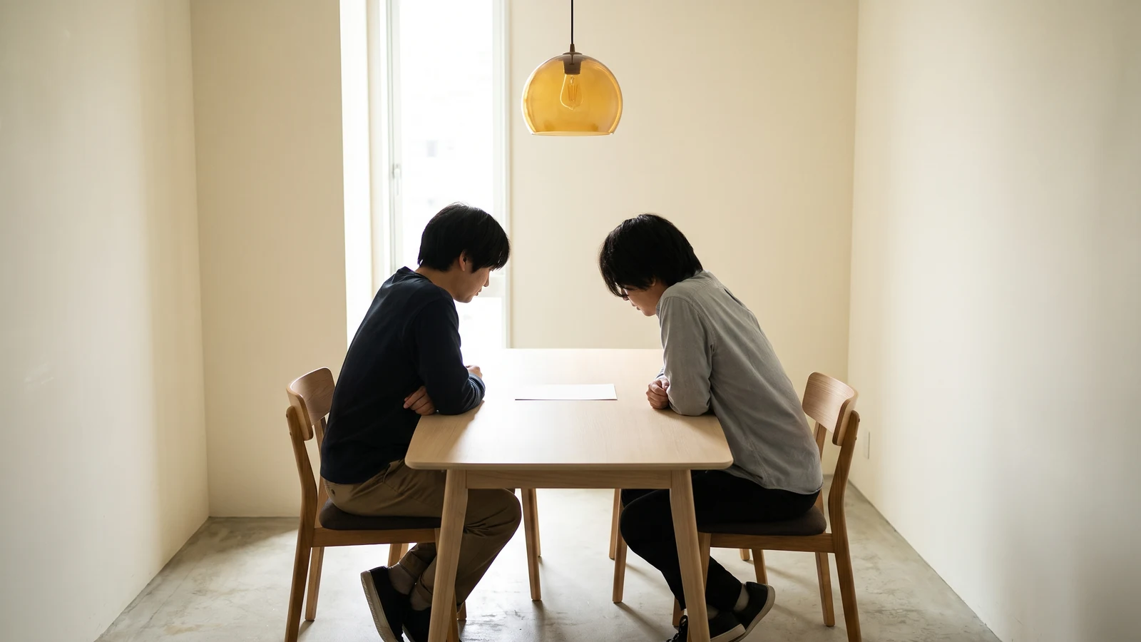 สองคนนั่งดูเอกสารบนโต๊ะประชุมในออฟฟิศที่มีแสงธรรมชาติ